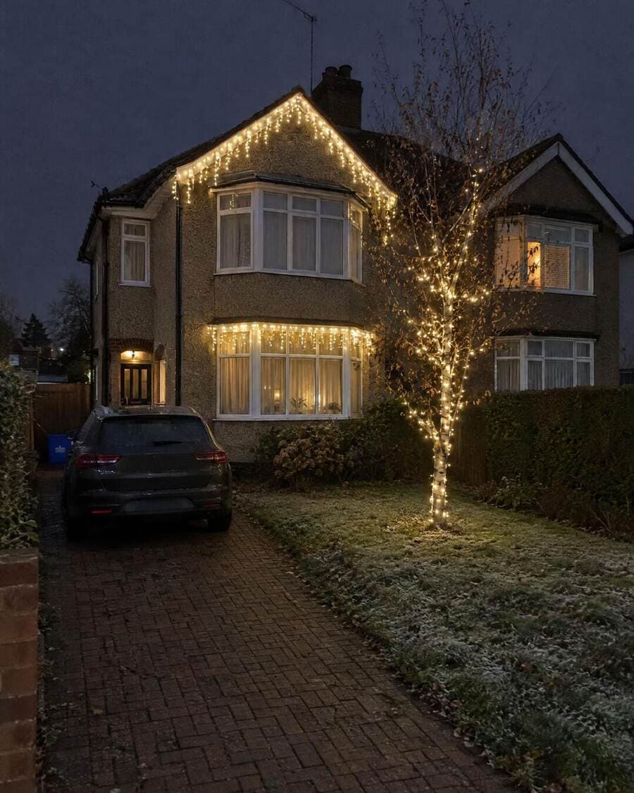 Semi-detached London home with Christmas icicle lights across the gutter and illuminated windows at night